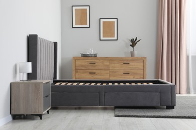 Photo of Comfortable bed with storage space for bedding under slatted base in stylish room