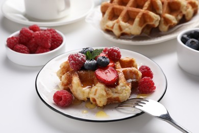 Photo of Delicious Belgian waffle with fresh berries and honey served on white table