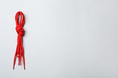 Red shoelaces on light background, top view. Space for text