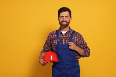 Photo of Professional builder with hard hat on yellow background