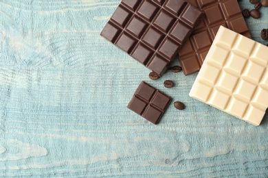 Photo of Delicious milk, dark and white chocolate bars on wooden table, top view