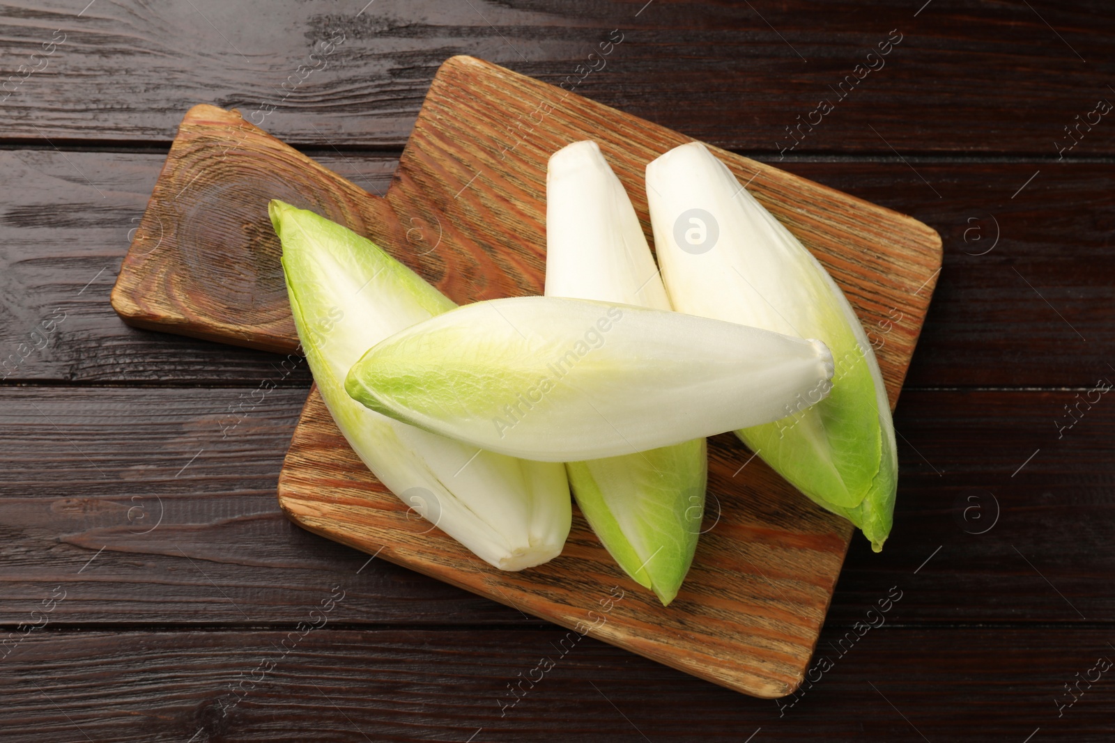 Photo of Raw ripe chicories on wooden table, top view