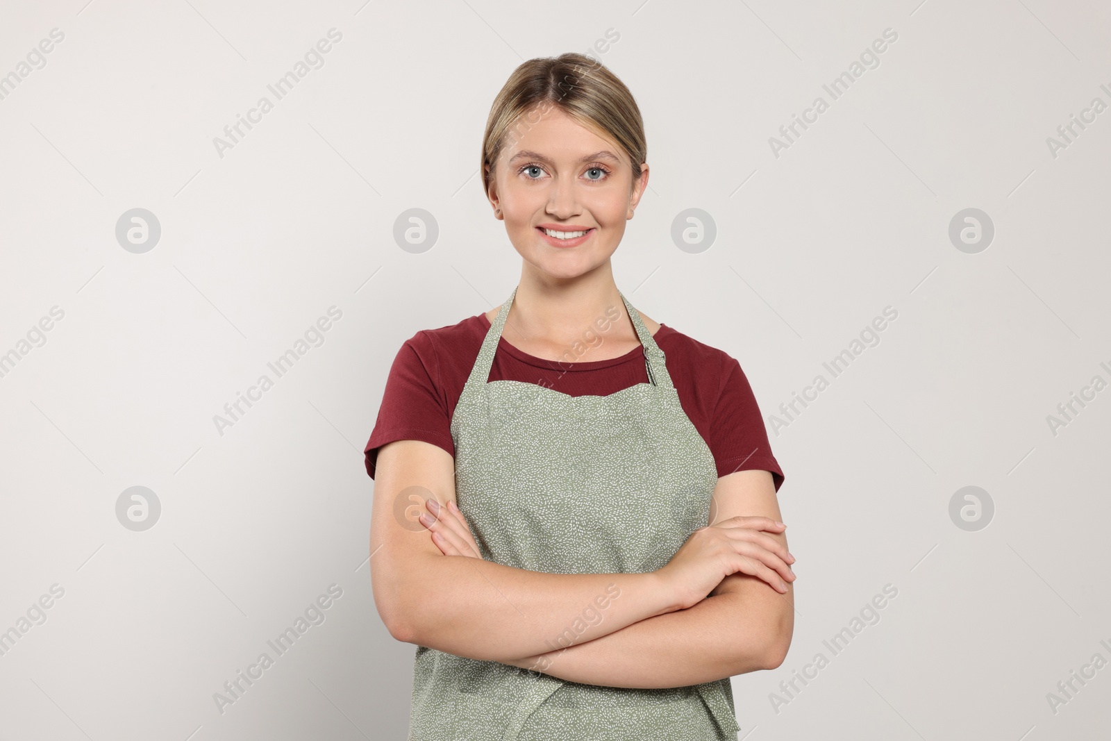 Photo of Beautiful young woman in clean apron on light grey background