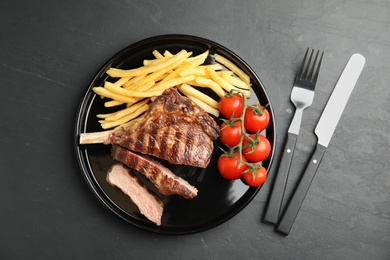 Tasty grilled steak served on black table, flat lay