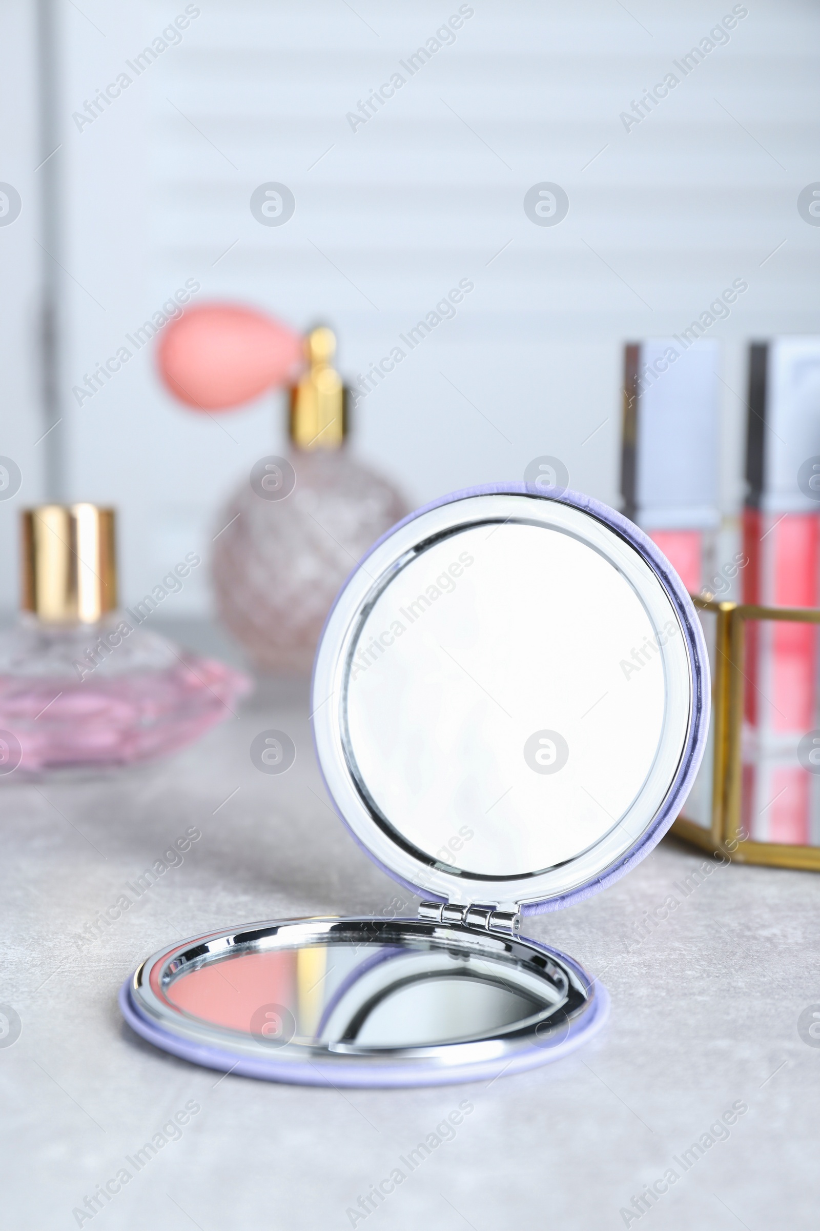 Photo of Stylish pocket mirror and cosmetic products on grey table