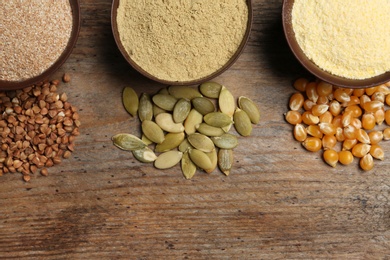 Flat lay composition with different types of flour and seeds on wooden background