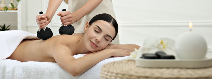 Image of Young woman receiving herbal bag massage in spa salon. Banner design