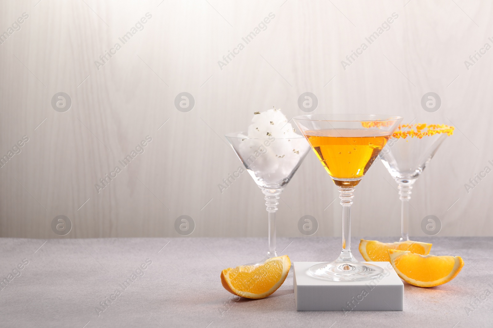 Photo of Tasty cotton candy cocktail and other alcoholic drinks in glasses on gray table, space for text