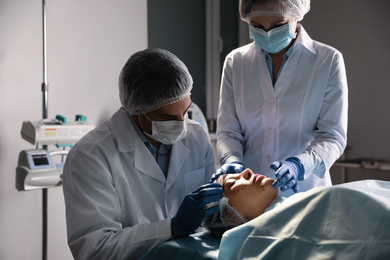 Photo of Doctor and nurse preparing female patient for cosmetic surgery in clinic