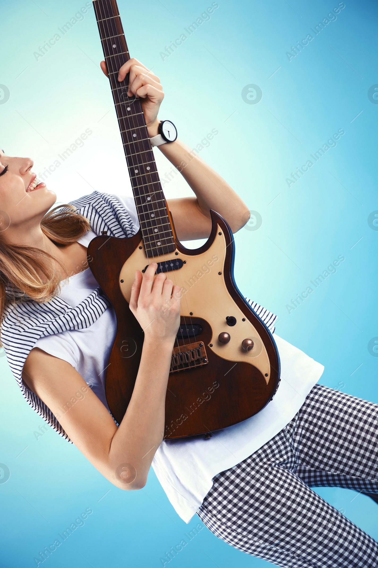 Photo of Young woman playing electric guitar on color background