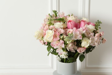 Beautiful bouquet of fresh flowers in vase near white wall, space for text