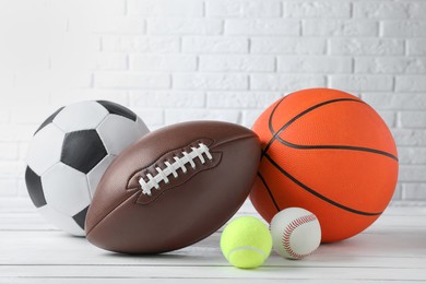 Photo of Set of different sport balls on white wooden table