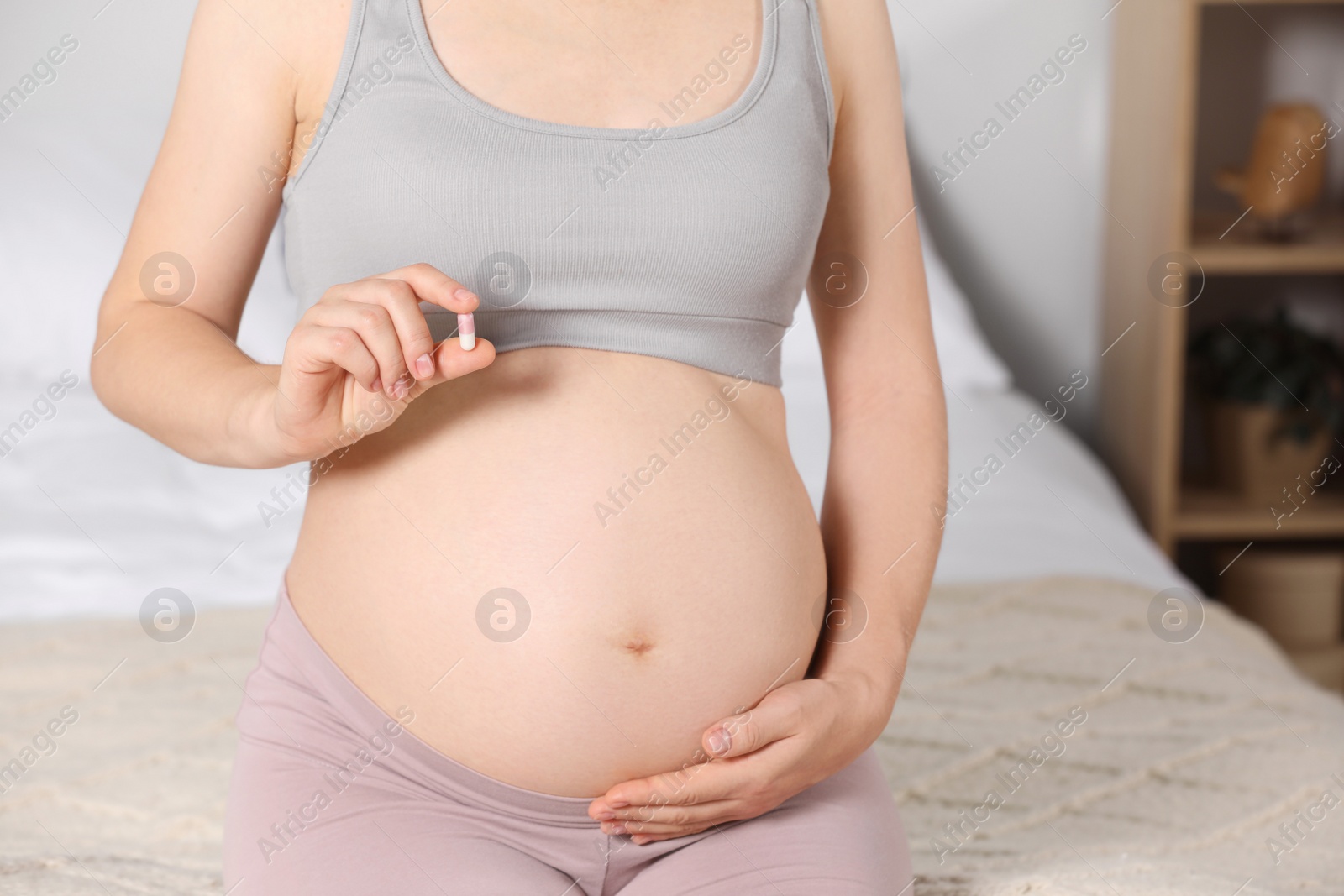 Photo of Pregnant woman taking pill at home, closeup