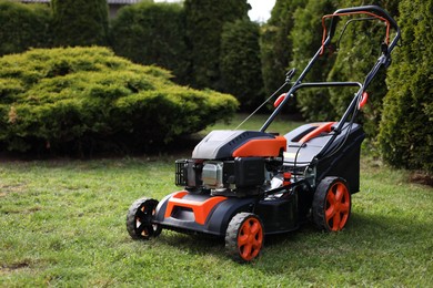 Photo of Modern lawn mower on green grass in garden