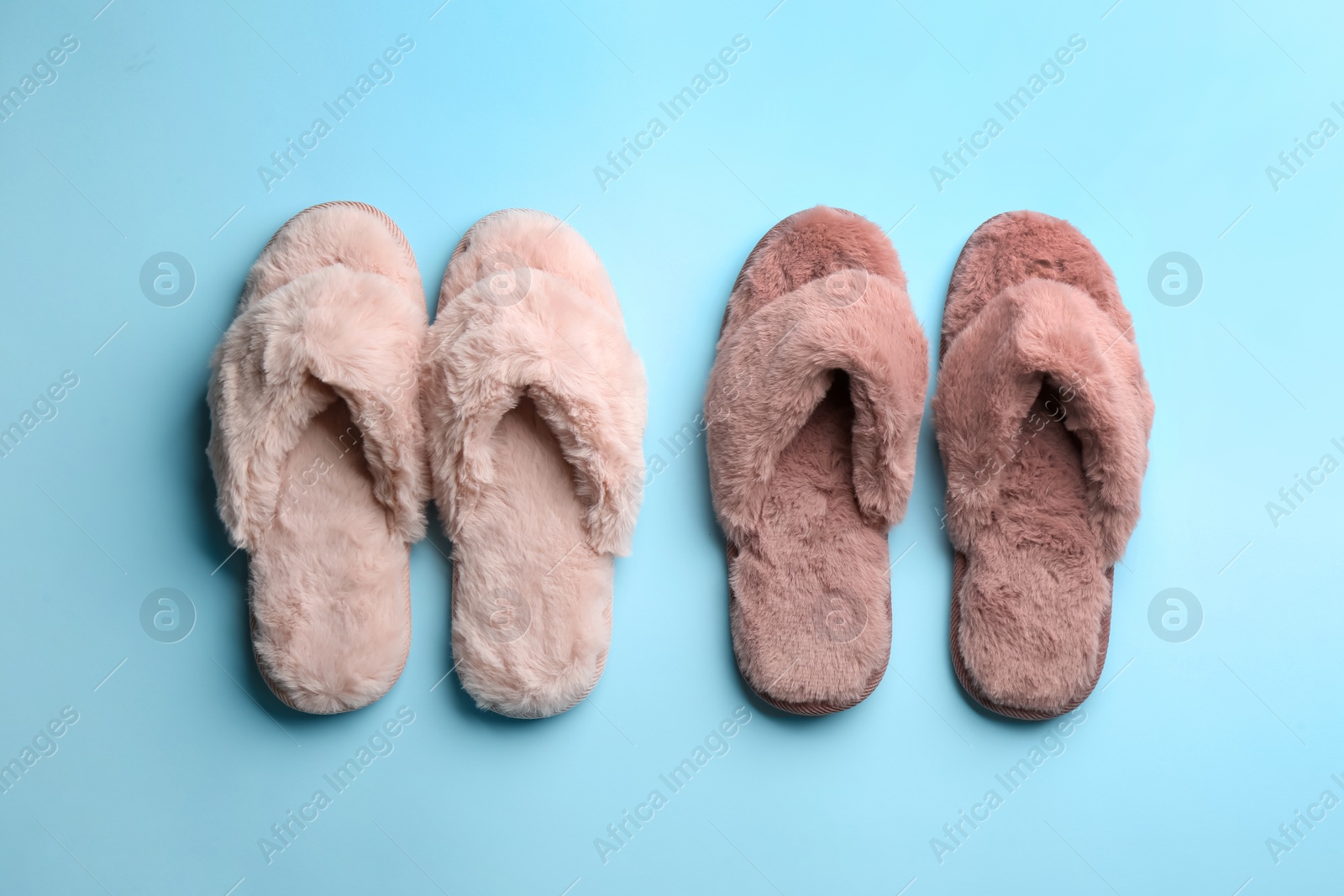 Photo of Different stylish soft slippers on light blue background, flat lay