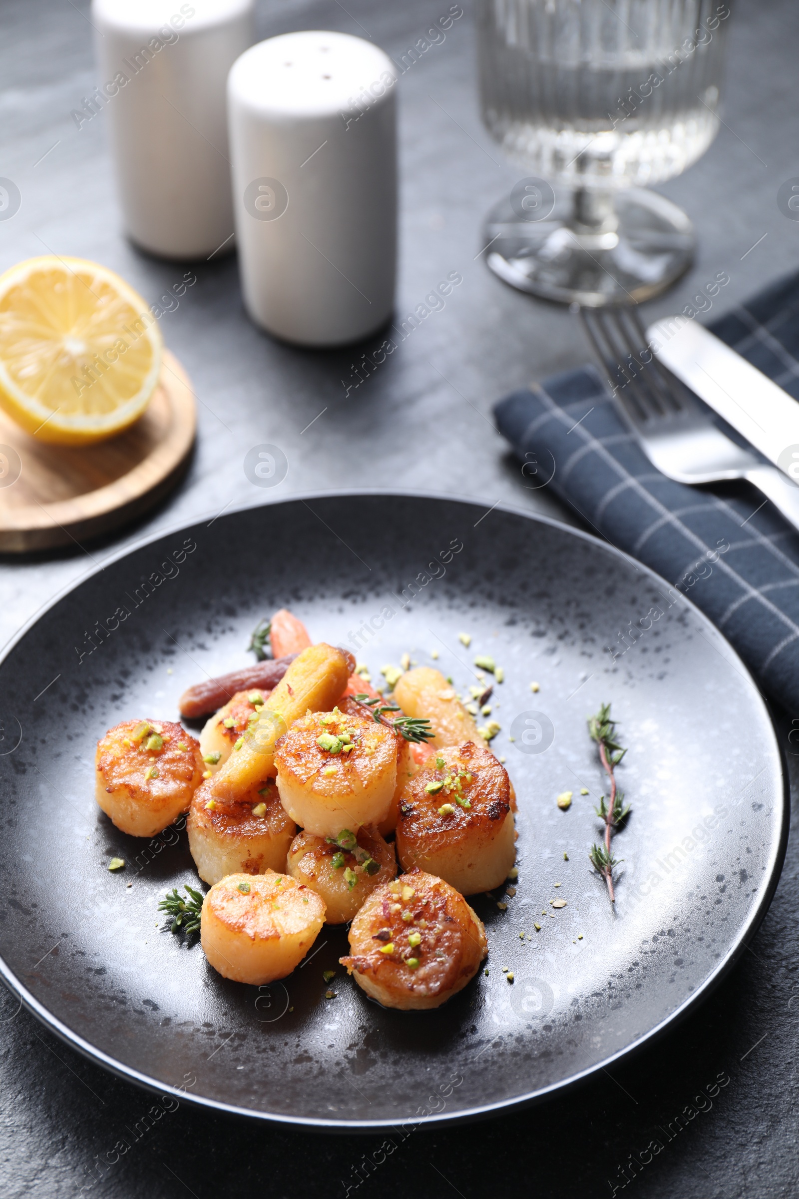 Photo of Delicious fried scallops served on dark gray table, closeup