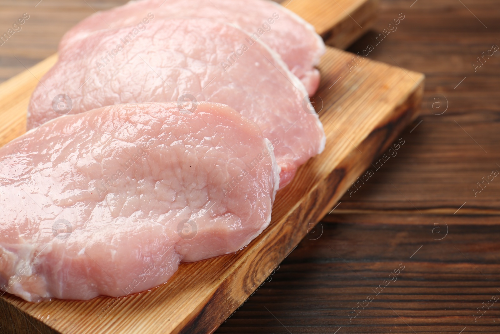 Photo of Pieces of raw pork meat on wooden table, closeup. Space for text