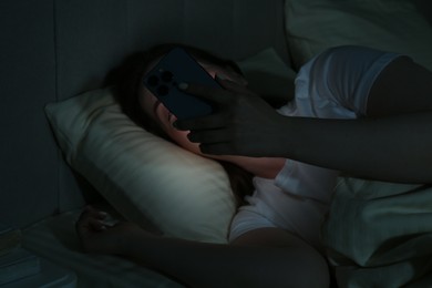 Woman using smartphone on bed at night. Internet addiction