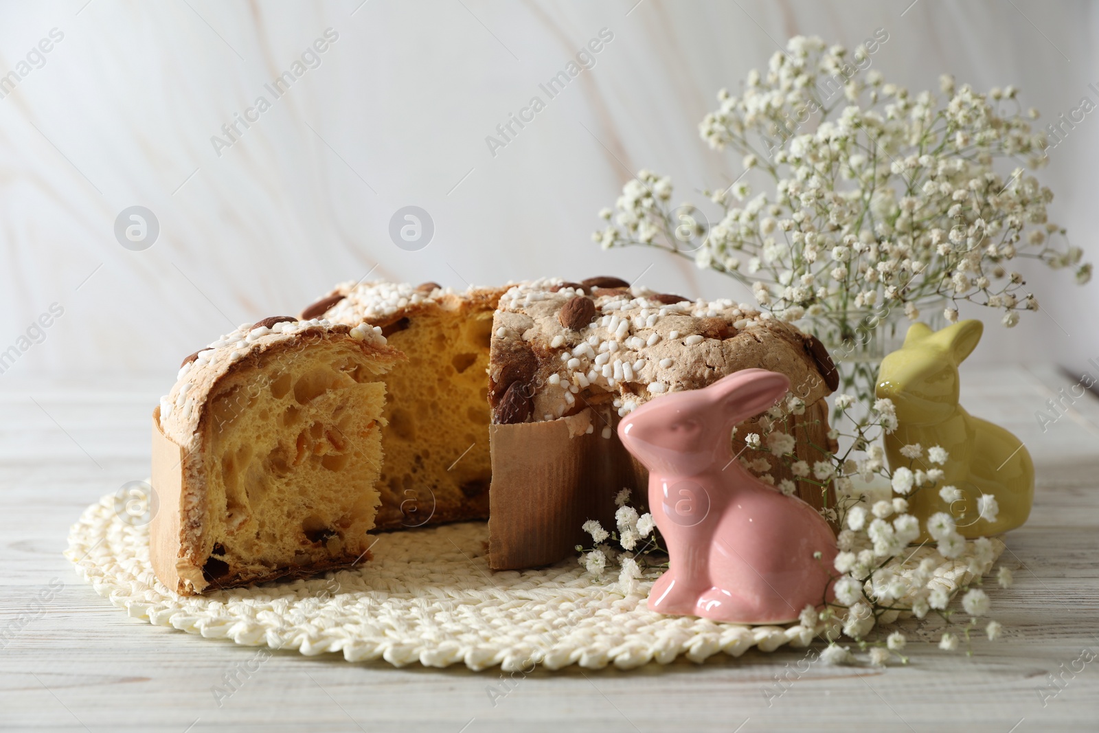 Photo of Delicious Italian Easter dove cake (traditional Colomba di Pasqua) and festive decor on white wooden table