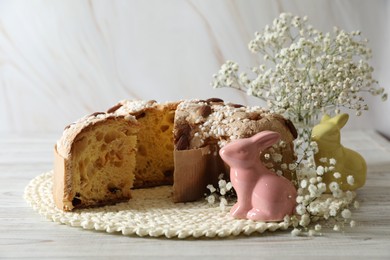Photo of Delicious Italian Easter dove cake (traditional Colomba di Pasqua) and festive decor on white wooden table