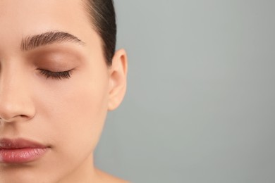 Photo of Young woman with perfect eyebrows on grey background, closeup. Space for text