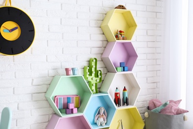 Colorful shelves near brick wall in child room interior