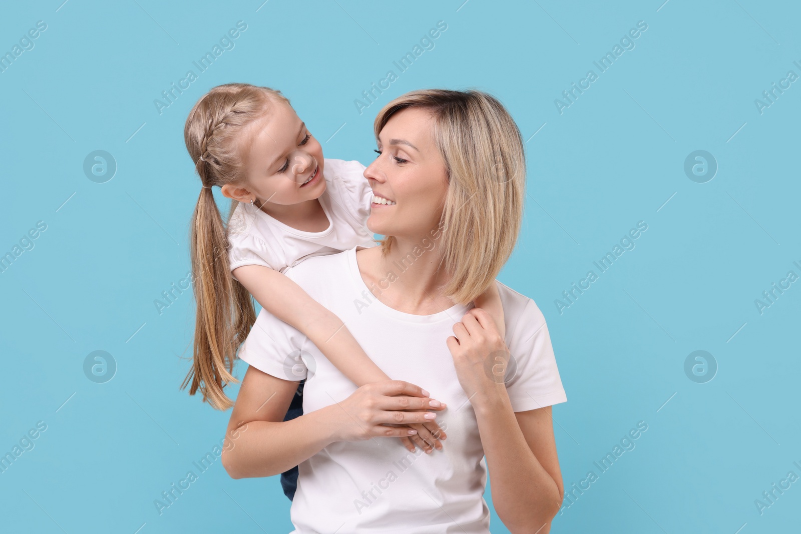 Photo of Family portrait of happy mother and daughter on light blue background