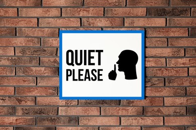 Image of Quiet Please sign with shush gesture image on red brick wall