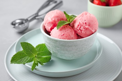 Photo of Delicious pink ice cream with mint in bowl on table