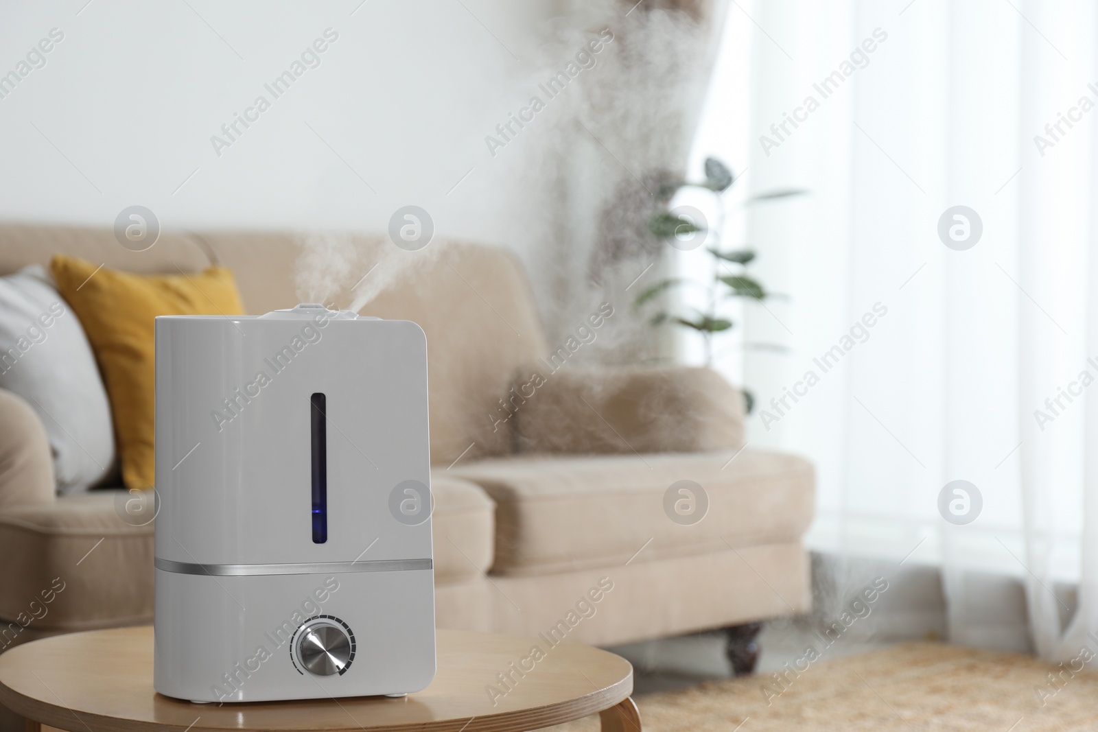 Photo of Modern air humidifier on wooden table indoors. Space for text