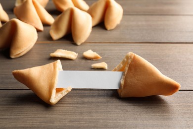 Photo of Tasty fortune cookies with predictions on wooden table, closeup. Space for text