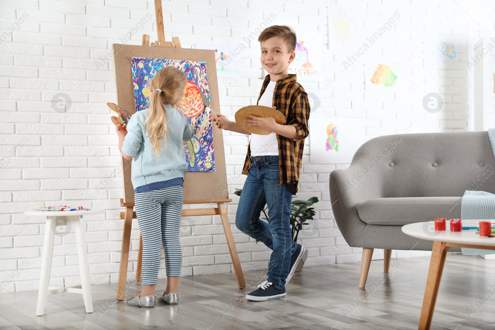 Photo of Cute little children painting on easel at home