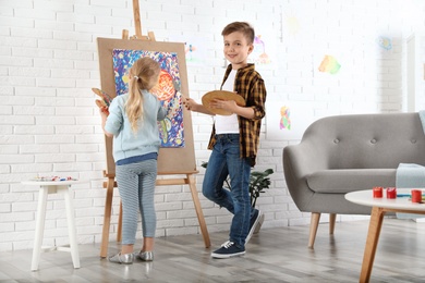 Photo of Cute little children painting on easel at home