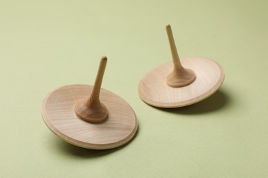 Photo of Two wooden spinning tops on green background, closeup