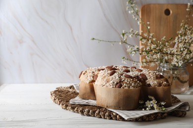 Photo of Delicious Italian Easter dove cake (Colomba di Pasqua) and flowers on white wooden table. Space for text