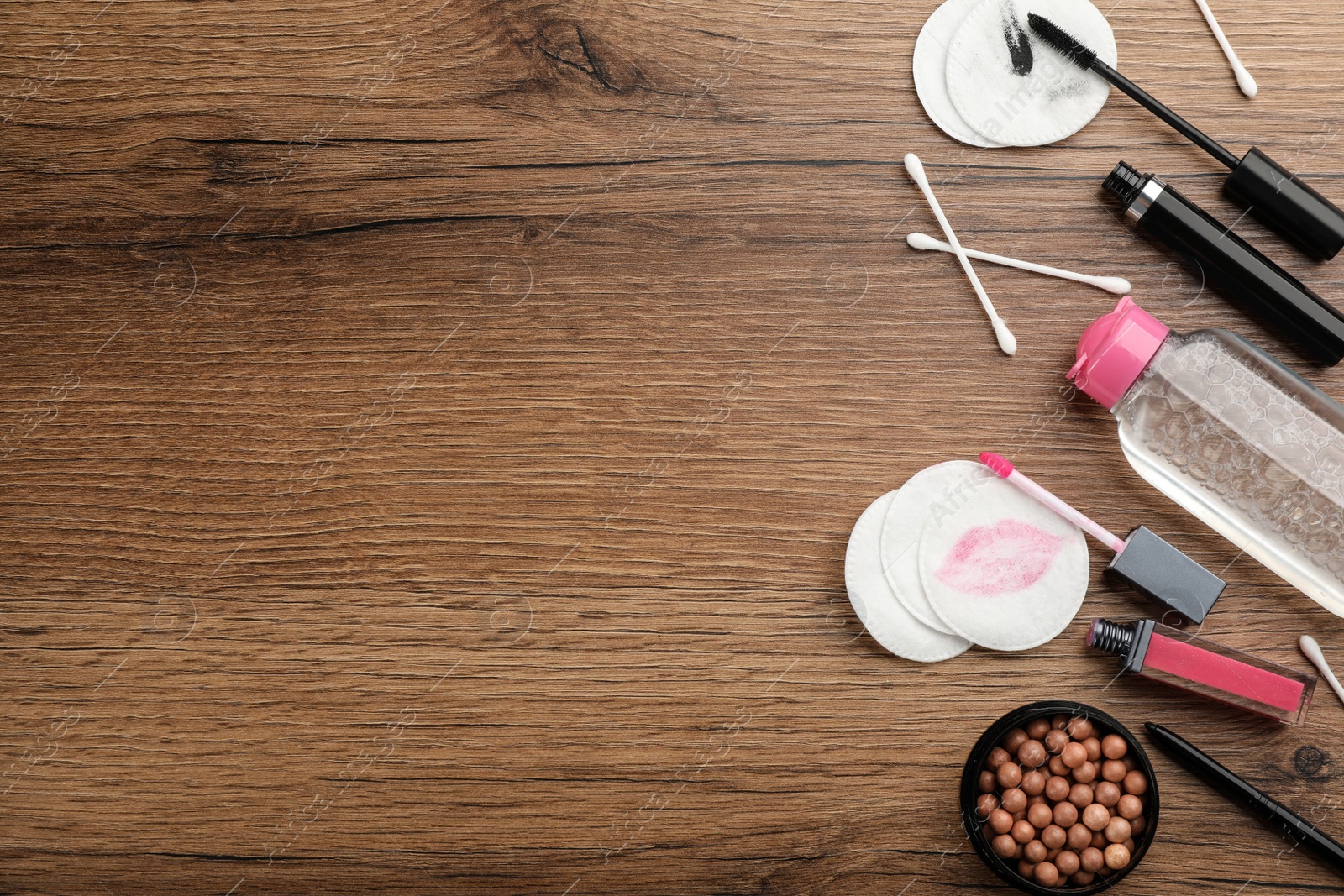 Photo of Dirty cotton pads, swabs, cosmetic products and micellar cleansing water on wooden background, flat lay. Space for text