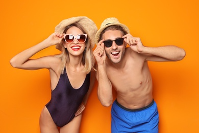 Photo of Happy young couple in beachwear and sunglasses on color background