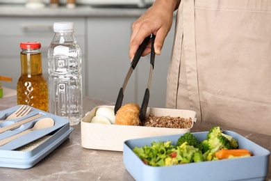 Photo of Woman preparing food for her child at table in kitchen, closeup. Healthy school lunch