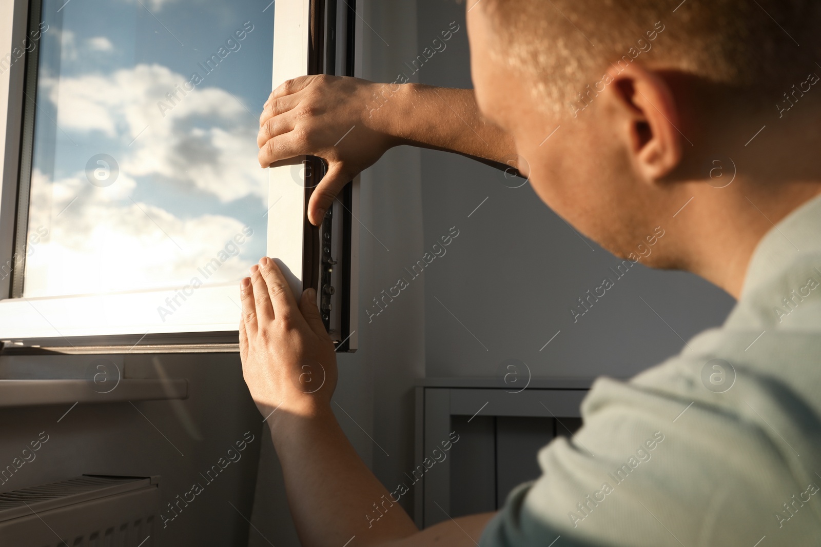 Photo of Construction worker putting sealing foam tape on window indoors, closeup