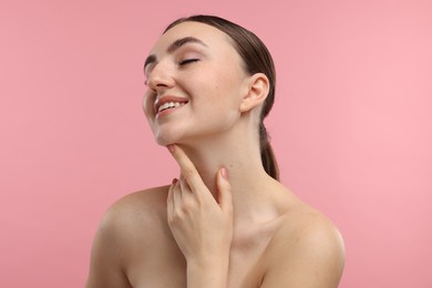 Smiling woman touching her chin on pink background