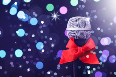 Image of Microphone with red bow against blurred lights, space for text. Christmas music. Bokeh effect