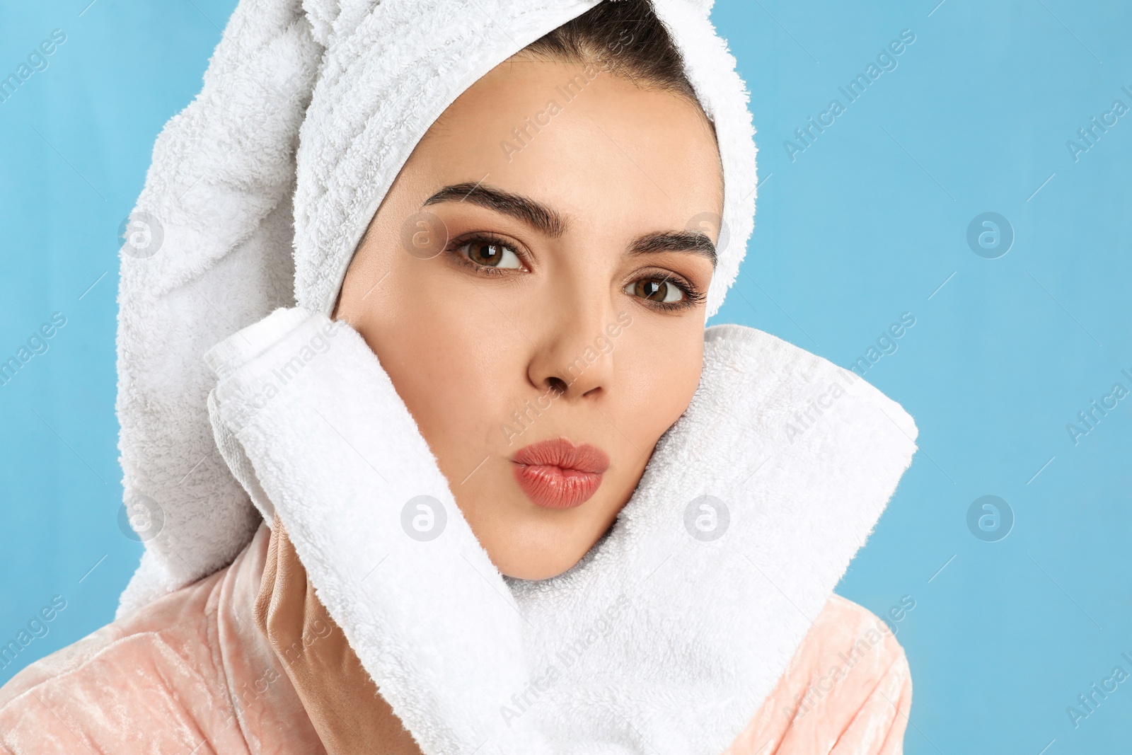 Photo of Young woman wiping face with towel on light blue background