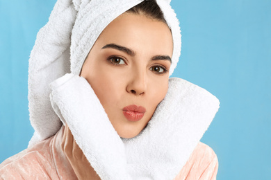 Photo of Young woman wiping face with towel on light blue background