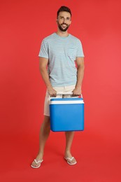 Photo of Happy man with cool box on red background