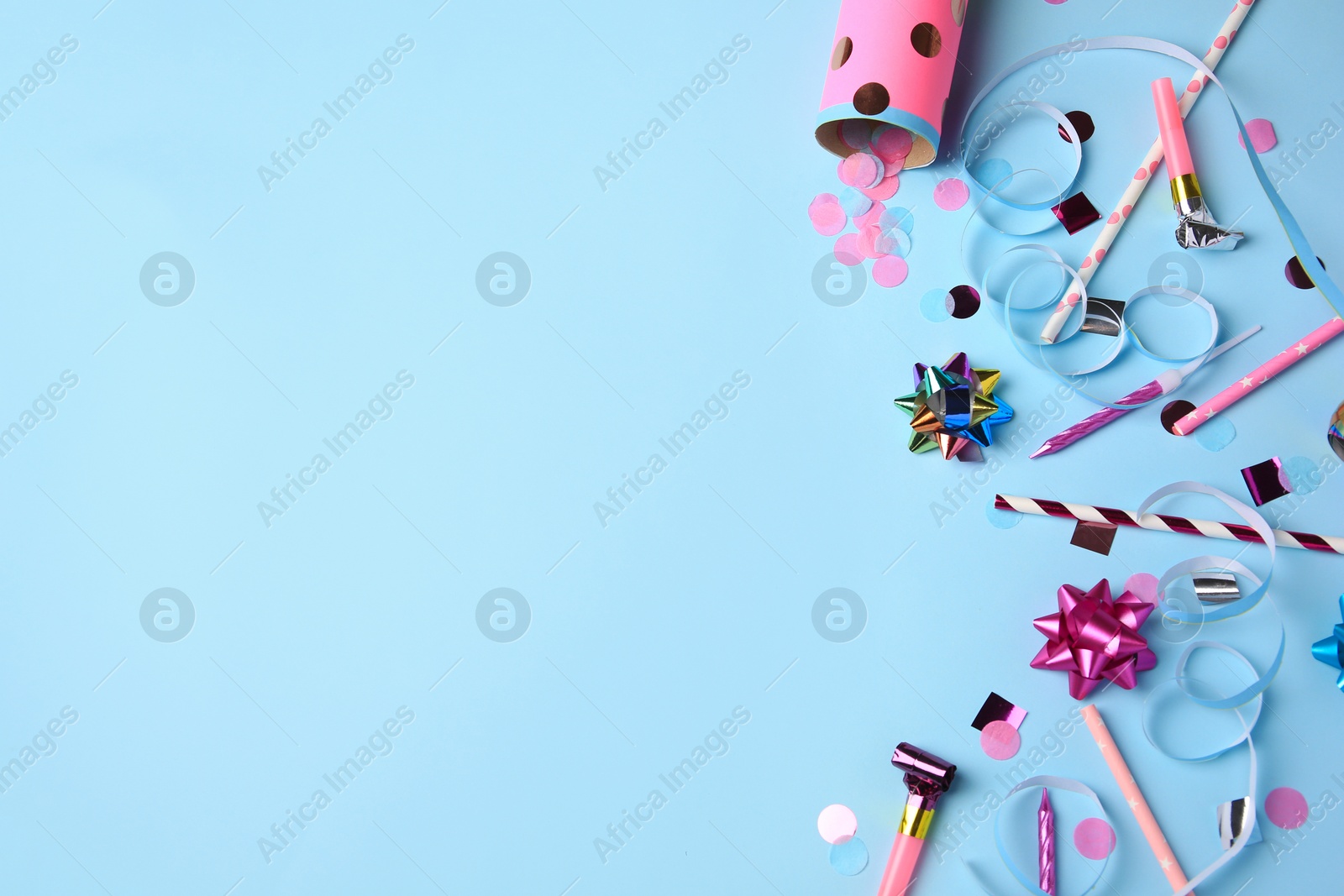 Photo of Party popper with confetti, blower and festive decor on light blue background, flat lay. Space for text