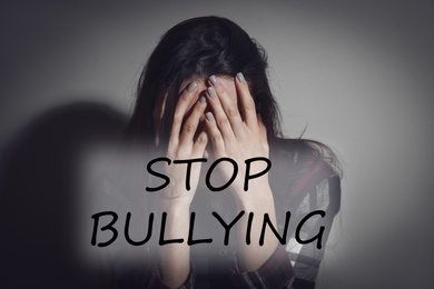 Message STOP BULLYING and abused teen girl crying near grey wall