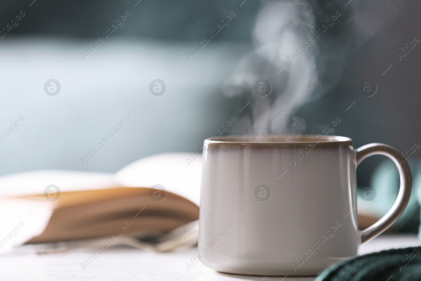 Photo of Cup of hot drink on white table against blurred background, space for text