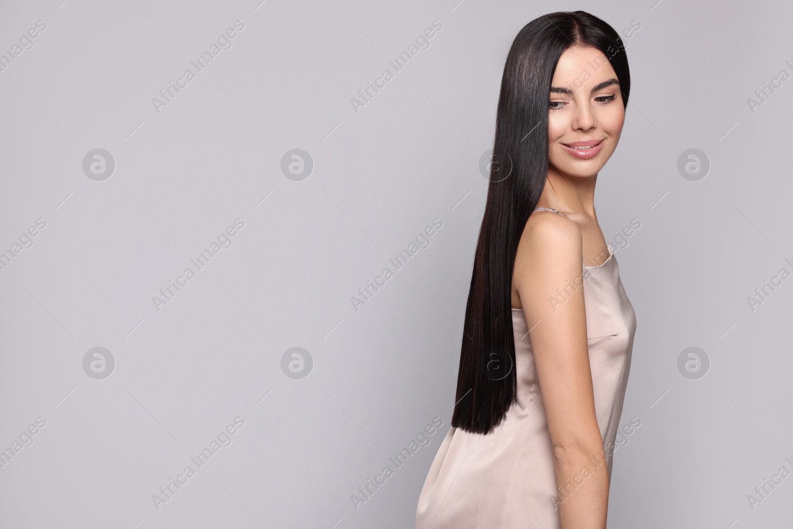 Photo of Portrait of beautiful young woman with healthy strong hair on light grey background, space for text