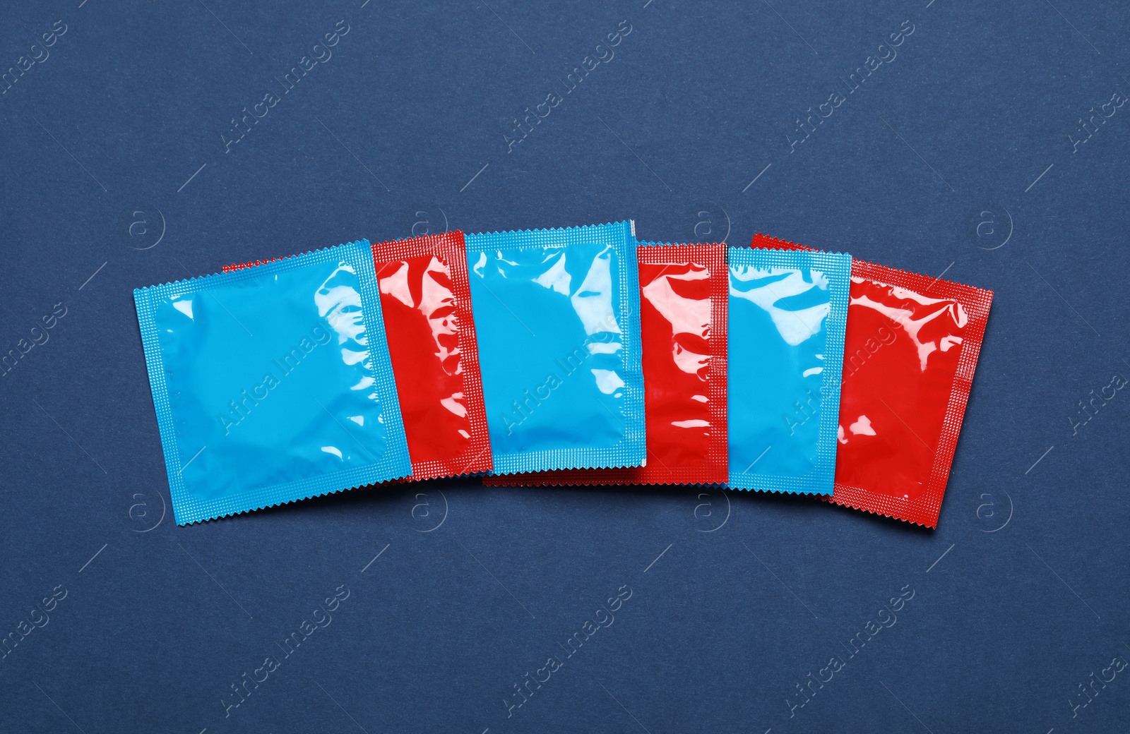 Photo of Condom packages on blue background, flat lay. Safe sex