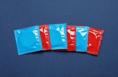 Photo of Condom packages on blue background, flat lay. Safe sex